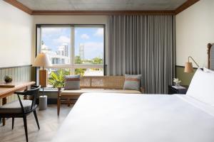 um quarto de hotel com uma cama, uma secretária e uma janela em The Balfour Hotel em Miami Beach