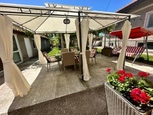 a patio with a table and an umbrella and flowers at При Наско in Shabla