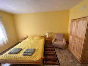um quarto amarelo com uma cama e uma cadeira em При Наско em Shabla