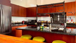 a kitchen with wooden cabinets and yellow stools at Hostal Laurita Beach in Montañita