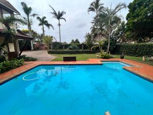 a swimming pool in a yard with palm trees at The Wood House in Empangeni