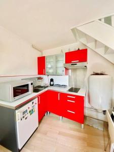 une cuisine avec des armoires rouges et des appareils électroménagers blancs dans l'établissement Cosy Duplex Centre Trouville parking gratuit, à Trouville-sur-Mer 14 autres photos
