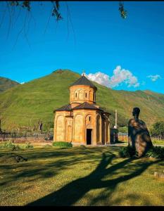a statue of a man sitting in front of a building at COZY house მყუდრო სახლი in Kazbegi +20 photos