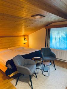 a bedroom with a large bed and two chairs at Apart Berghof Steinbock in Sankt Leonhard im Pitztal