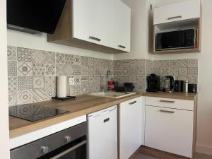 a kitchen with white cabinets and a microwave at Au calme proche centre-ville, studio rénové avec équipements neufs et parking privé in Gap