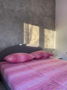 een slaapkamer met een bed met roze lakens en een raam bij Apartman Gabi in Subotica