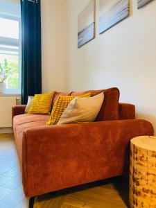 ein braunes Sofa mit gelben Kissen im Wohnzimmer in der Unterkunft Apartament Pod Lipami in Olsztyn