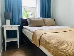 Schlafzimmer mit blauen Vorhängen, einem Bett und einem Tisch in der Unterkunft Apartament Pod Lipami in Olsztyn