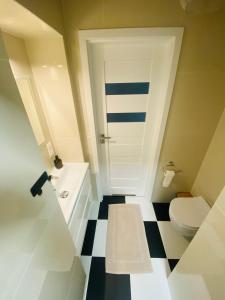 ein Badezimmer mit einem weißen WC und einem schwarz-weißen Boden in der Unterkunft Apartament Pod Lipami in Olsztyn