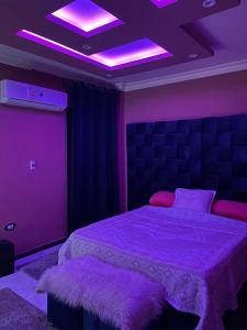 Un dormitorio con una cama con luces moradas. en سيدي بشر بحري امام بير مسعود, en Alejandría