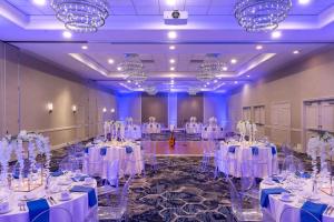 a banquet hall with white tables and chairs and chandeliers at Juniper Hotel Cupertino, Curio Collection by Hilton in Cupertino