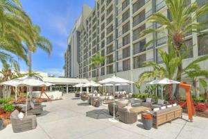 a patio with chairs and umbrellas in front of a building at Hilton Irvine/Orange County Airport in Irvine