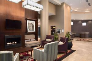 a lobby with a fireplace and chairs and a tv at Embassy Suites Saint Louis - Downtown in Saint Louis