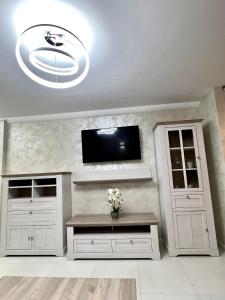 シビウにあるBO│NO Apartmentの白いキャビネットと壁掛けテレビが備わる客室です。
