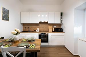a kitchen with white cabinets and a wooden table at Villa Antique in Novi Vinodolski