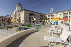 einen Pool mit Stühlen und Sonnenschirmen sowie einen Spielplatz in der Unterkunft Cedar Point Hotel Breakers in Sandusky