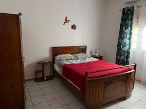 um quarto com uma cama de madeira e um cobertor vermelho em Kaza Ohana proche de Malendure - maison 8 à 11 personnes em Bouillante