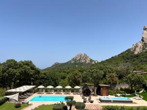 een resort met een zwembad en bergen op de achtergrond bij Antica Fonte Holiday Homes in San Pantaleo