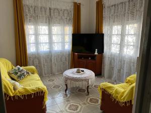 sala de estar con mesa, 2 sillas y TV en Kaza Ohana proche de Malendure - maison 8 à 11 personnes, en Bouillante