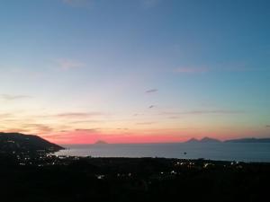 una puesta de sol sobre el océano con montañas en la distancia en Casa vacanze Sabbie di Giove, en Patti