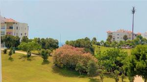 a park with trees and a building in the background at magnifique appartement de trois chambres avec vue sur le golf et la mer Marina Asilah in Asilah