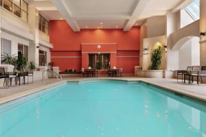 a large pool in a hotel with tables and chairs at Embassy Suites by Hilton Los Angeles Downey in Downey