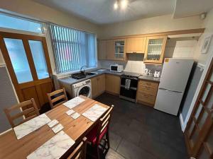 a small kitchen with a table and a refrigerator at Lovely house & driveway parking in Kidsgrove