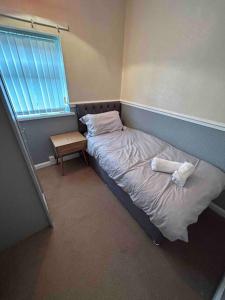 a small bedroom with a bed and a window at Lovely house & driveway parking in Kidsgrove