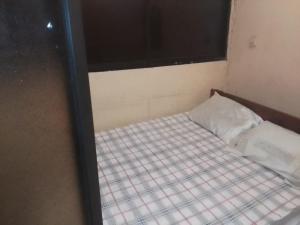 a small bed in a room with a window at Hospedaria Zac in Luanda