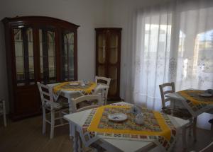 a dining room with two tables and chairs and curtains at A Casa di Zia in Oschiri