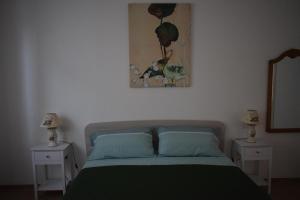 a bedroom with a bed with two nightstands and a painting at A Casa di Zia in Oschiri