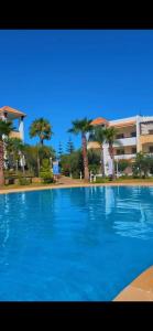 een groot blauw zwembad voor een gebouw bij magnifique appartement de trois chambres avec vue sur le golf et la mer Marina Asilah in Asilah