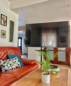 sala de estar con sofá de cuero y TV de pantalla plana en Agradable casa con jacuzzi climatizado exterior en pleno Urdaibai, en Busturia
