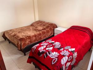 1 dormitorio con 2 camas y edredón rojo en Dtos las brisas en La Banda