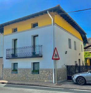 a white and yellow house with a car parked in front at Agradable casa con jacuzzi climatizado exterior en pleno Urdaibai in Busturia