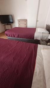 two beds in a room with red sheets at Residencial familiar El Valle in Copiapó