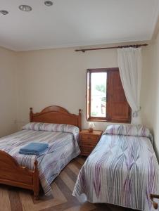 1 dormitorio con 2 camas y ventana en Casa Nieves, en Villaviciosa