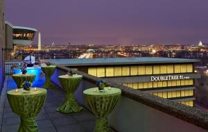 a rooftop bar with green tables on top of a building at DoubleTree by Hilton Washington DC – Crystal City in Arlington
