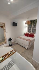 een witte slaapkamer met een bed en een bad bij La Damajuana, Casa Rural in Montejaque