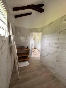 baño con paredes de mármol blanco y lavabo en gîte de forêt de Guadeloupe, en Petit-Bourg