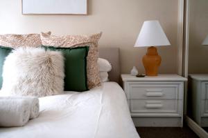 a bed with green and white pillows and a lamp at Popular Central Location I NEW LINEN I Gated Estate I STAY DUBBO in Dubbo