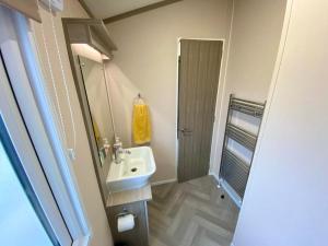 ein Bad mit einem Waschbecken, einem Spiegel und einer Dusche in der Unterkunft The Lodge in Selsey