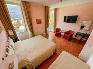 una camera d'albergo con due letti e una televisione di Caroline Hotel a Brusimpiano