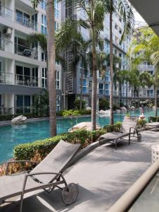 a resort pool with benches and palm trees at Centara Avenue 2 Bedrooms Pool View in Pattaya Central