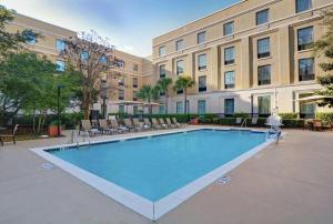 a large swimming pool with chairs and a building at Hampton Inn Charleston-Daniel Island in Charleston