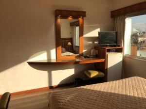 a bedroom with a desk with a mirror and a bed at Hotel London Palace in Montevideo