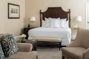 ニューオーリンズにあるザ ルーズベルト ホテル ニューオーリンズ - ウォルドーフ アストリア ホテルズ & リゾーツのベッド1台と椅子2脚が備わるホテルルームです。
