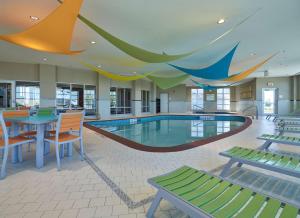 a swimming pool in a building with tables and chairs at Hampton Inn by Hilton Calgary Airport North in Calgary