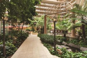 a walkway in a building with trees and plants at Embassy Suites Birmingham in Birmingham