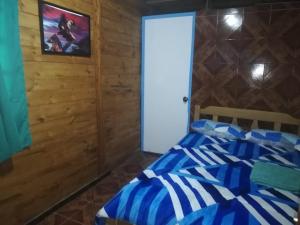 Un dormitorio con una cama azul y blanca y una puerta en SHERANPAZ, en Oxapampa